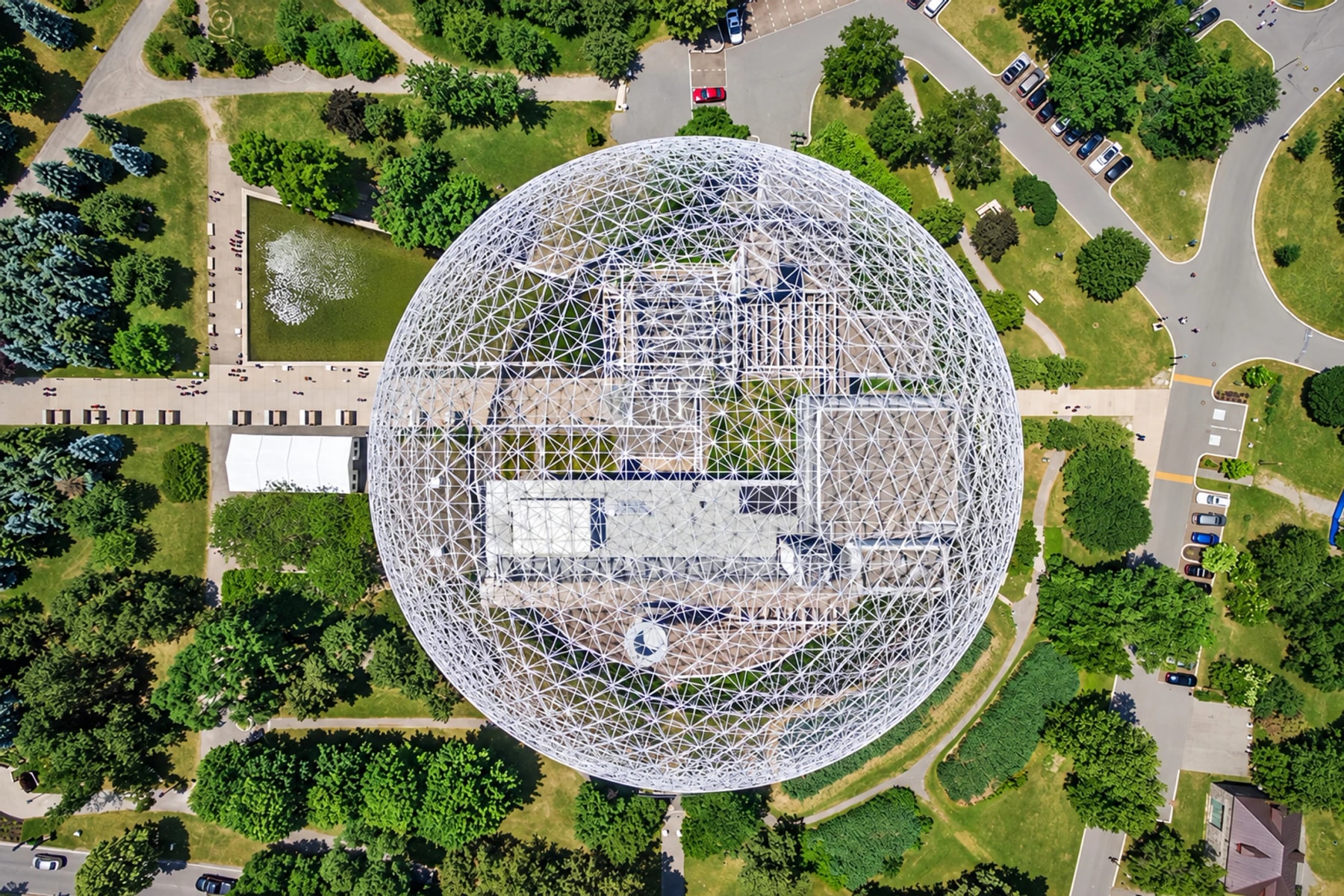 Vue aérienne du dôme blanc de la Biosphère entouré d’arbres et de sentiers.
