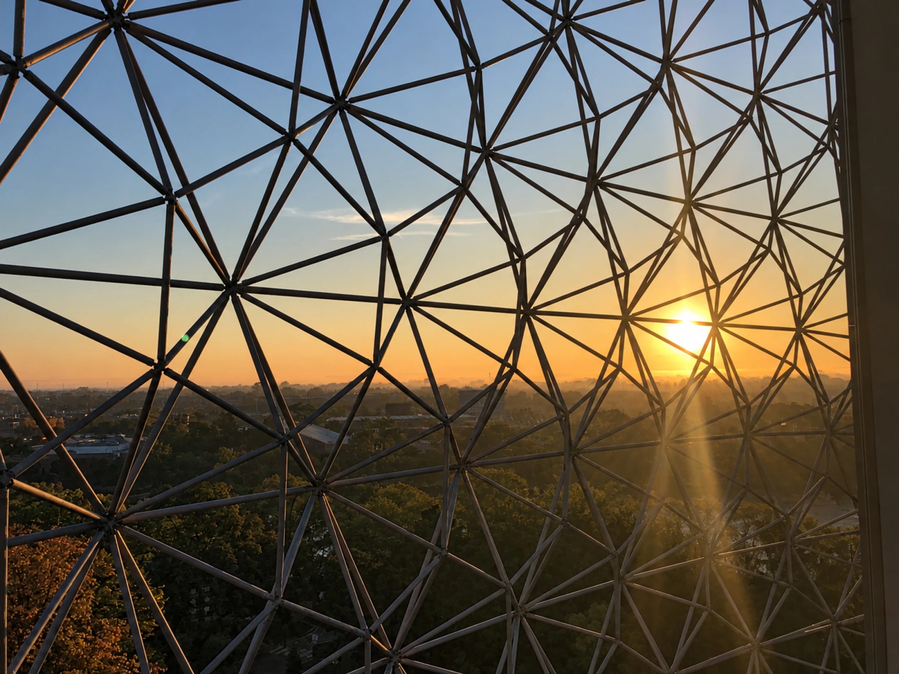Sunset viewed through the Biosphère’s geometric metal framework.