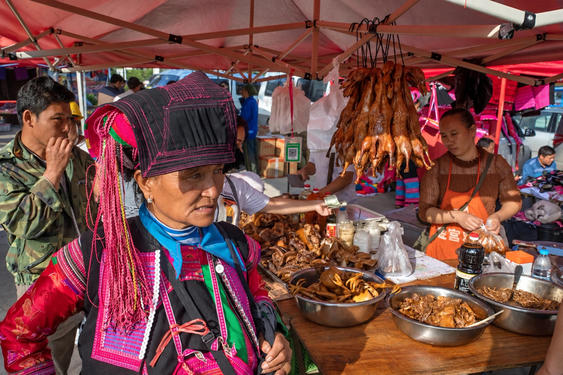 Une femme en costume traditionnel brodé dans un marché sous des auvents rouges.