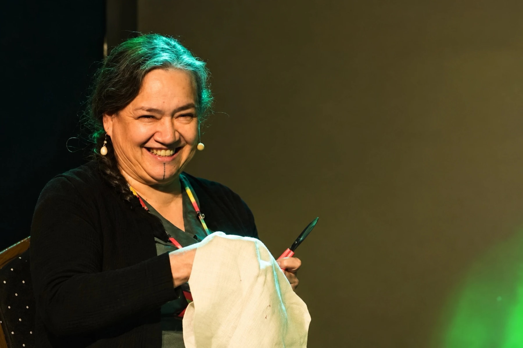 A smiling performer holds a piece of fabric onstage.