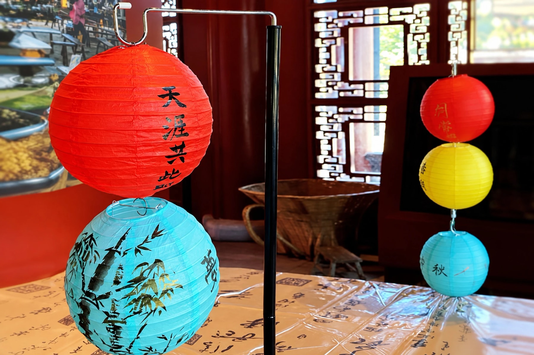 Des lanternes en papier colorées ornées d’écriture chinoise et de bambous peints.