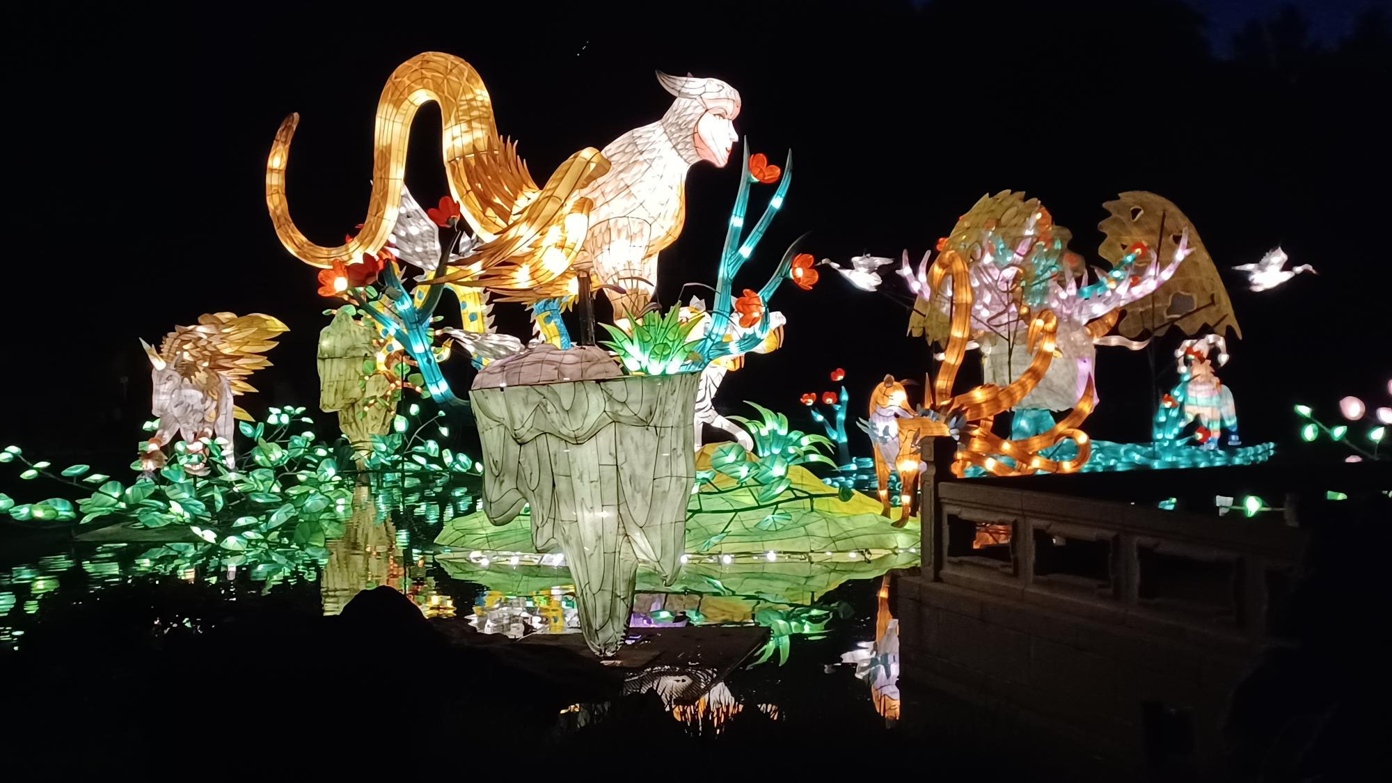 Des lanternes lumineuses de créatures fantastiques disposées sur un étang la nuit.