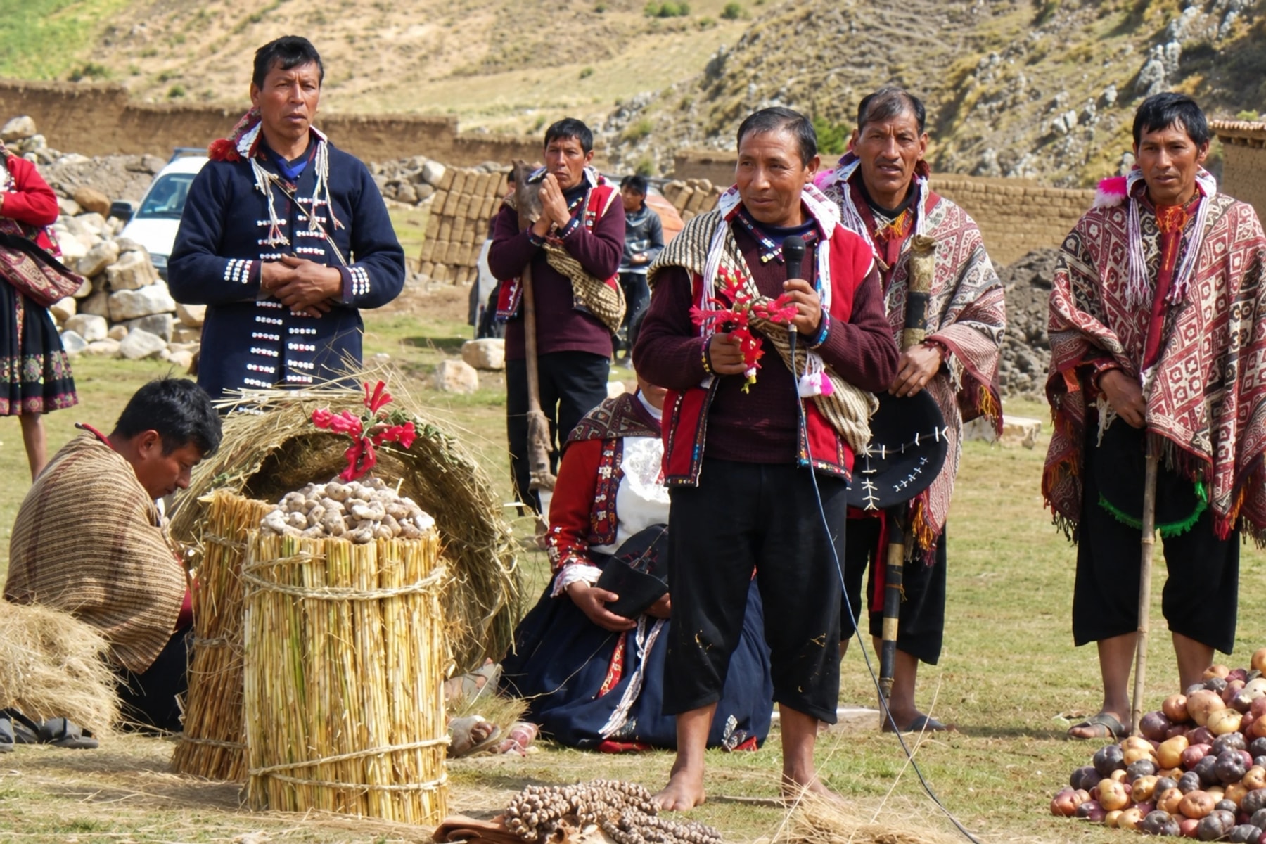 Un groupe en vêtements à motifs se rassemble autour d’un panier de pommes de terre dehors.