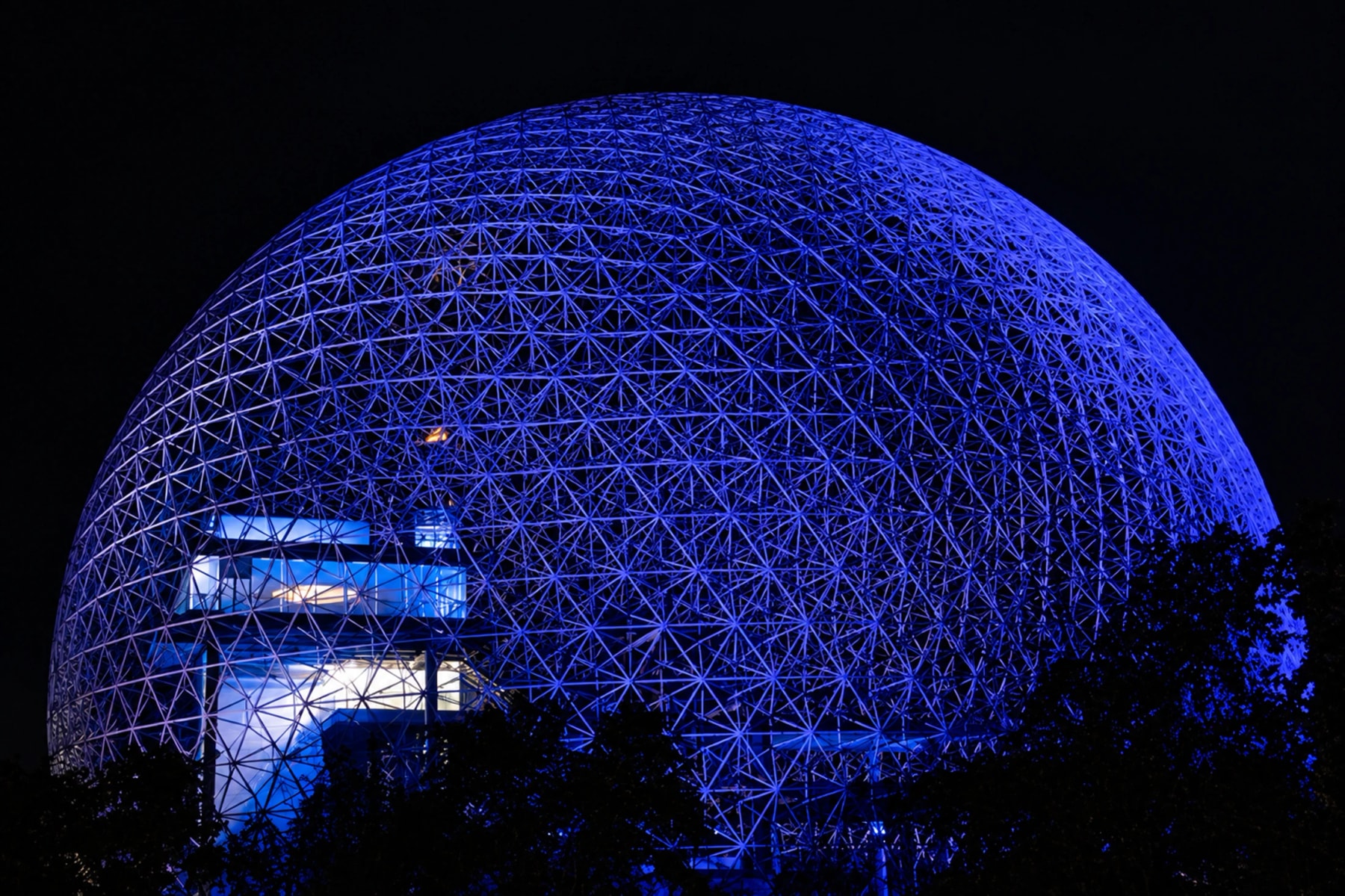 Le dôme de la Biosphère illuminé en bleu dans la nuit.