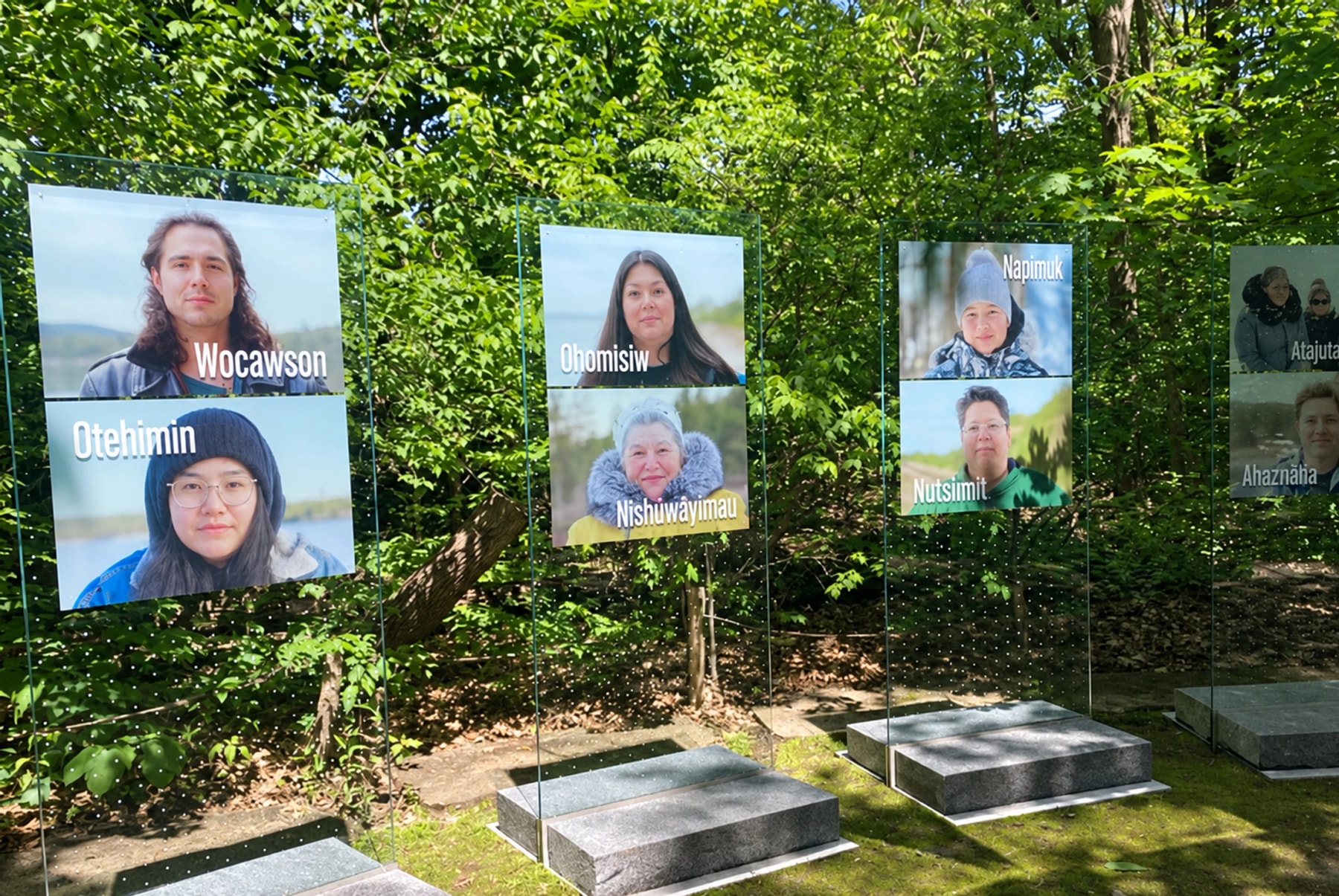 Portrait panels displayed among trees along a garden path.