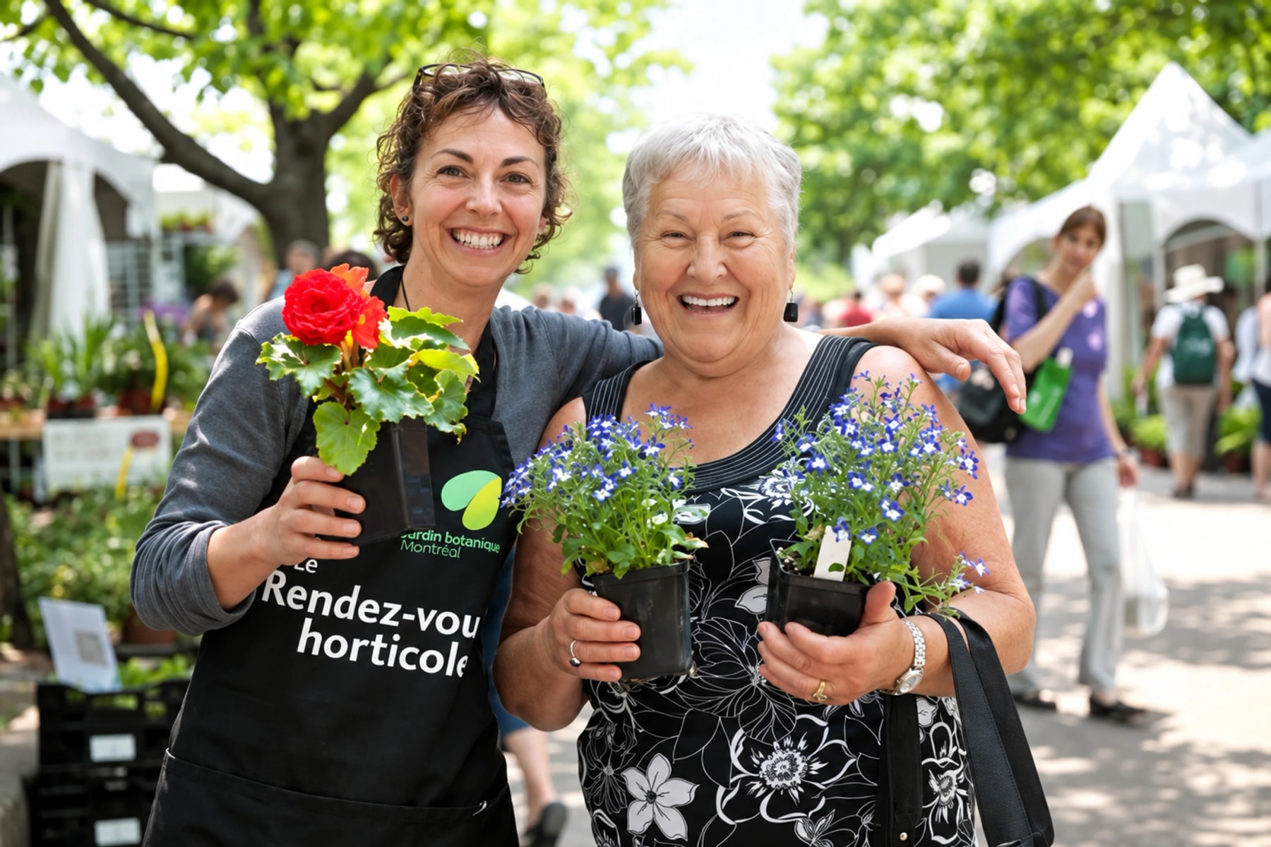 Deux personnes souriantes tiennent des plantes fleuries lors d’un événement horticole.