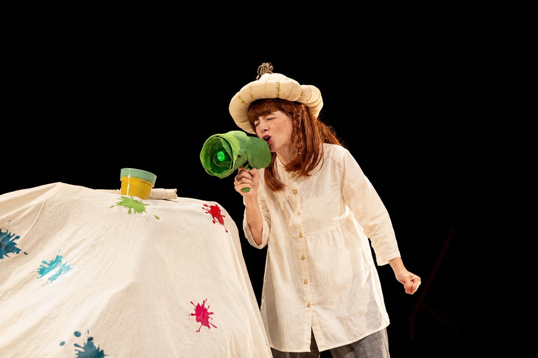 A costumed performer speaks through a green megaphone onstage.