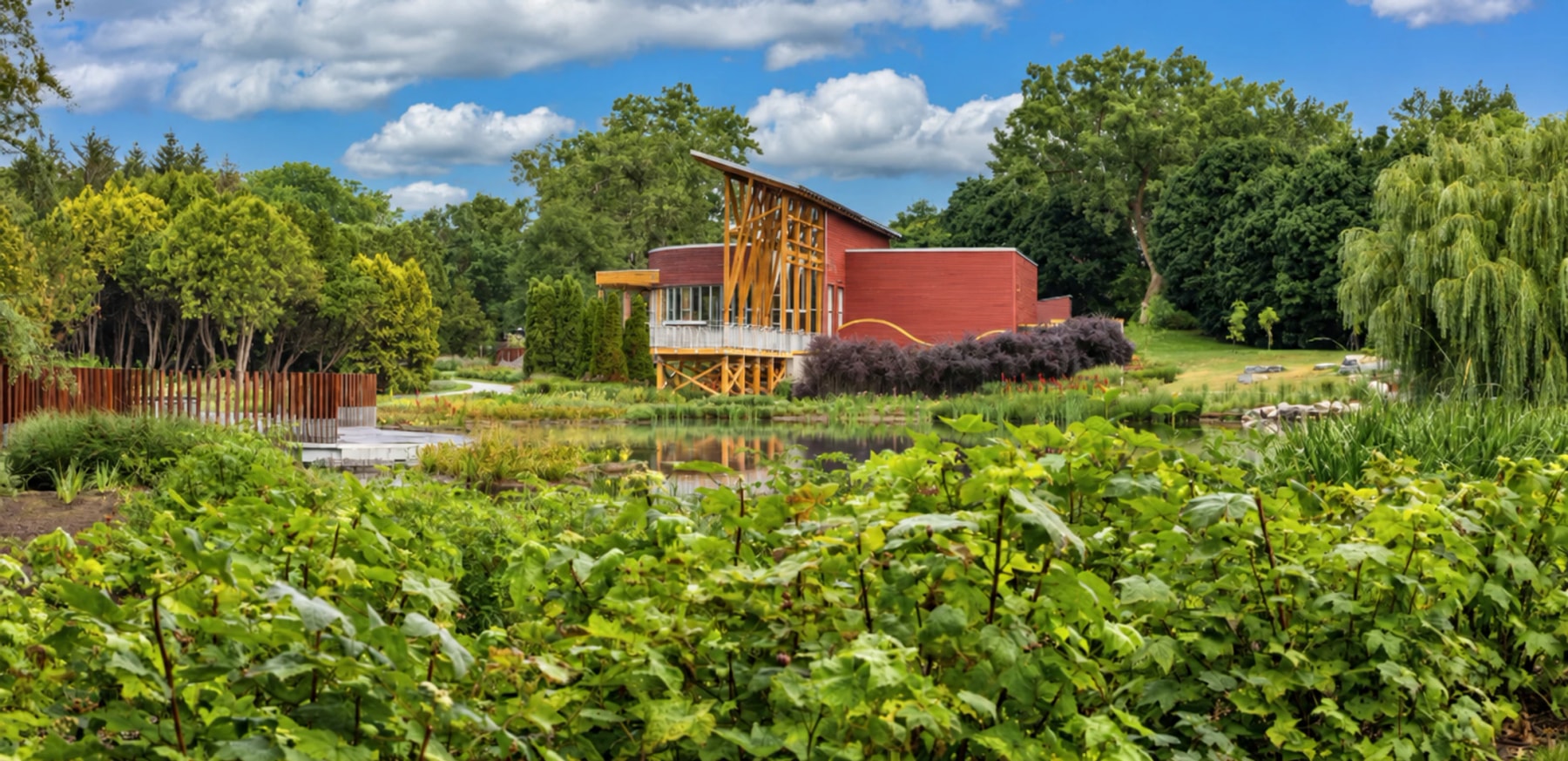 Un bâtiment rouge et une tour en bois se dressent derrière un jardin luxuriant.