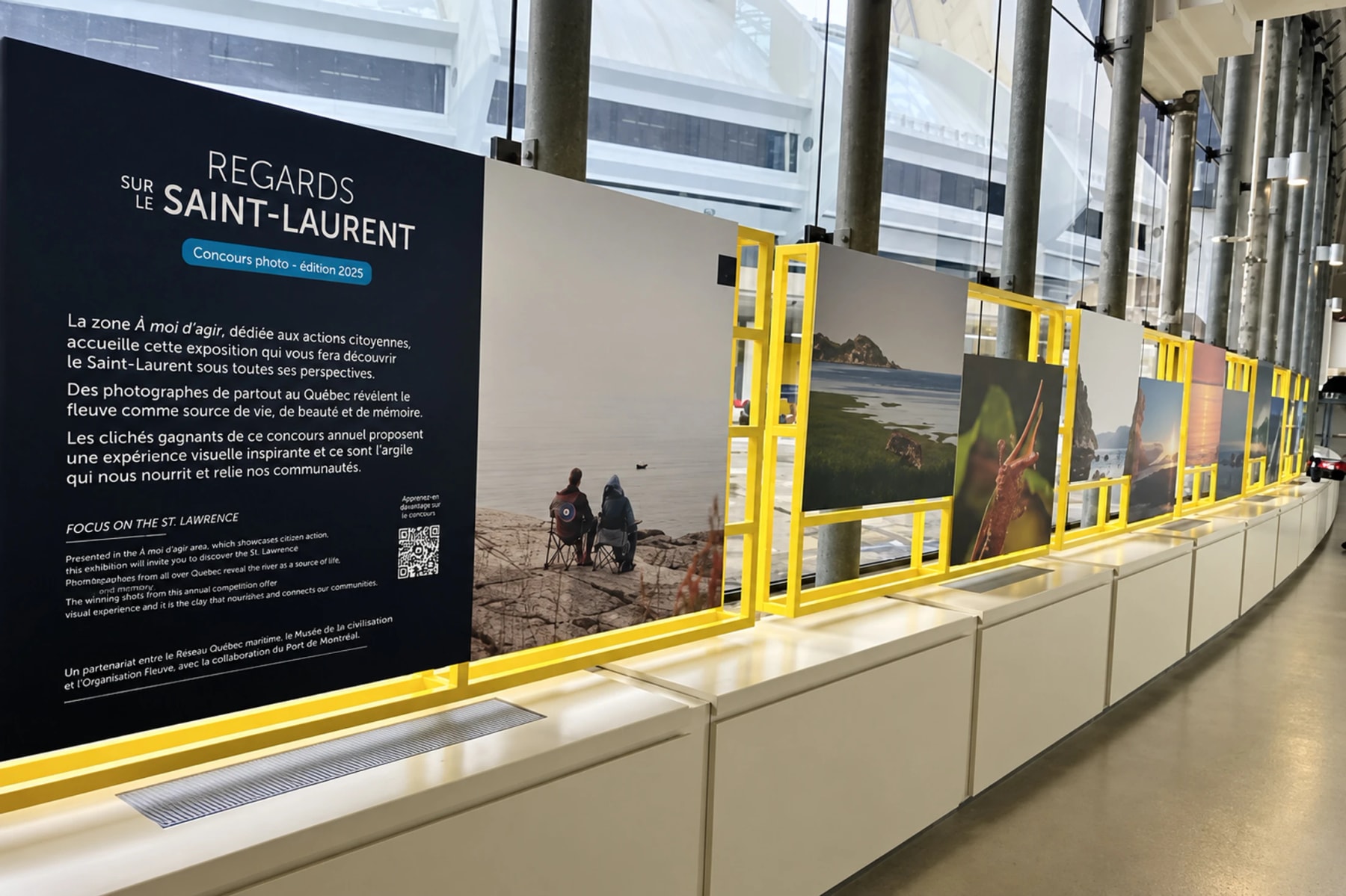 Photographs of the St. Lawrence displayed in yellow frames along a windowed corridor.