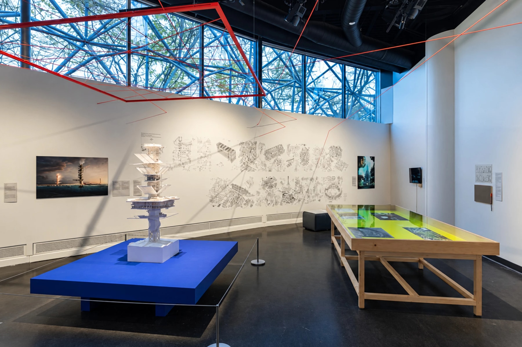 Architectural models and drawings displayed in a bright exhibition gallery.