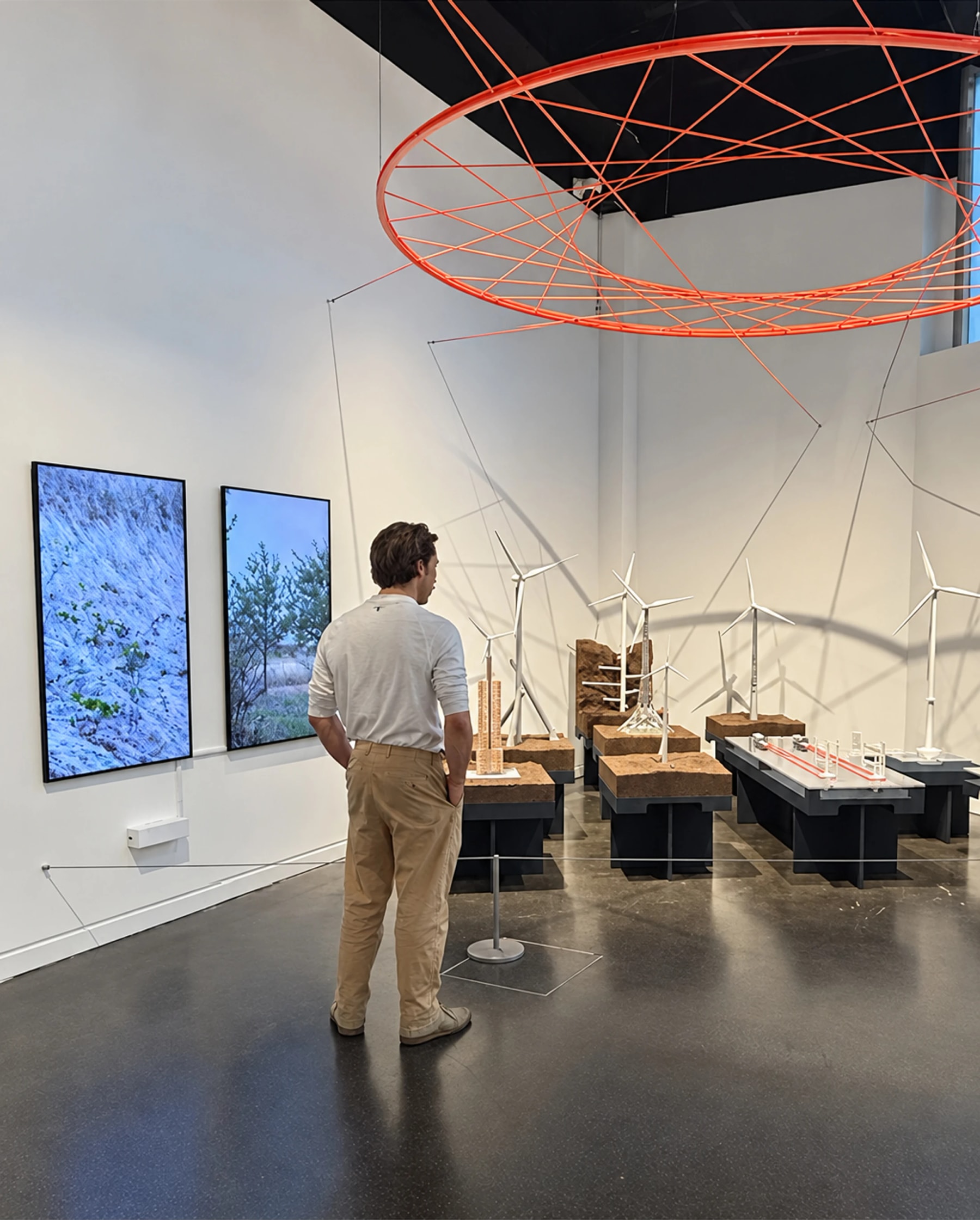 A visitor studies exhibits beneath a large suspended orange ring.